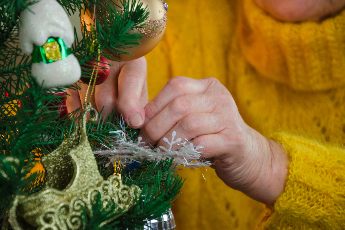 Senior Woman Hanging Ornaments on Christmas Tree_Vivage